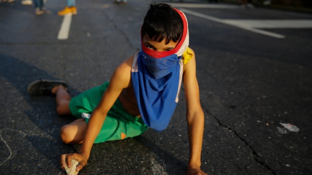 A young demonstrator writes slogans on the pavement during a protest against the government of President Nicolás Maduro in the streets of Caracas, Venezuela, on February 2nd, 2019.