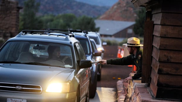 A park ranger Lee Wilson (R) passes out park information to visitors at the entrance to Zion National Park in Springdale, Utah.