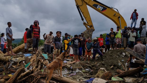 Indonesians watch as rescue workers dig through rubble looking for victims of the recent flash floods on March 19th, 2019, in Sentani, West Papua province, Indonesia. At least 89 people have died and nearly 7,000 have been displaced from their homes after three straight days of heavy rain led to massive flash flooding, which brought down massive trees and boulders from the surrounding mountains, crushing hundreds of homes.