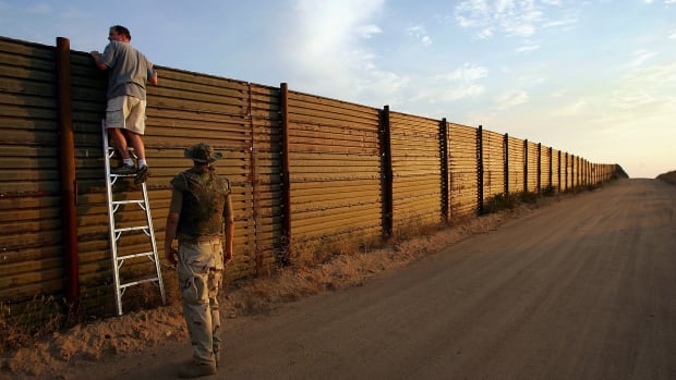 Volunteers look over the U.S.–Mexico border fence.