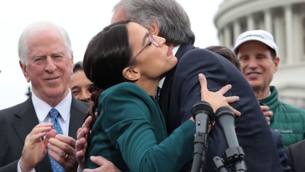 Representative Alexandria Ocasio-Cortez and Senator Ed Markey hug each other as other Congressional Democrats look on during a news conference unveiling a Green New Deal resolution in front of the U.S. Capitol on February 7th, 2019, in Washington, D.C.