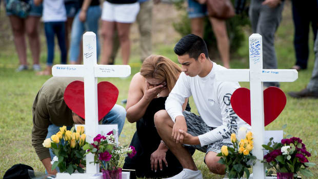 People visit a cross for Christopher Stone at a memorial for the victims of the Santa Fe High School shooting on May 21st, 2018, in Santa Fe, Texas.