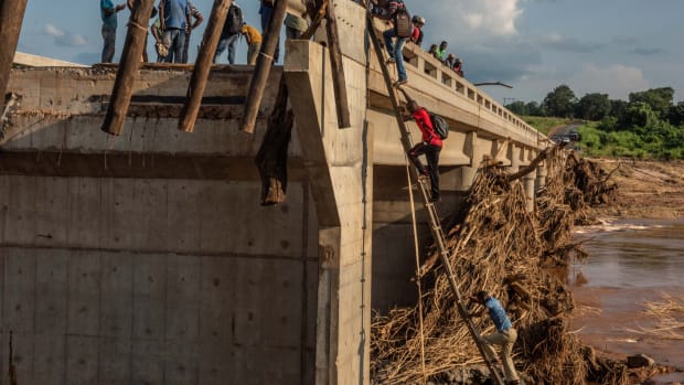 People scale a broken bridge, damaged during Cyclone Idai, to cross the Lucite River on March 26th, 2019, outside of Magaro, Mozambique. The storm caused the river to overflow and flood nearby villages. At least 156 bodies have been found in the surrounding area.