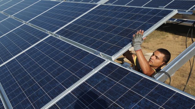 A worker installs solar panels containing photovoltaic cells.