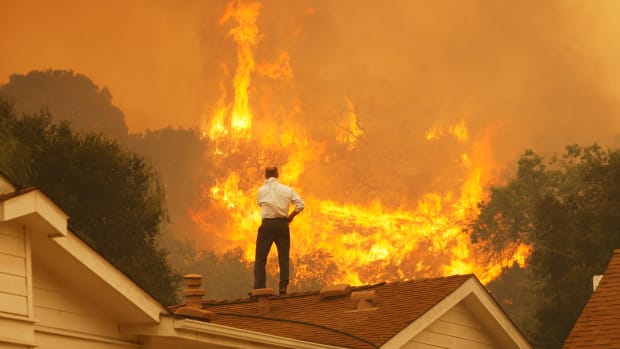 A man on a rooftop looks at approaching flames as the Springs fire continues to grow on May 3rd, 2013, near Camarillo, California.