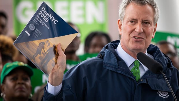 New York City Mayor Bill de Blasio holds up a copy of the One NYC 2050 plan as he speaks about the city's response to climate change at Hunter's Point South Park on April 22nd, 2019, in the Queens borough of New York City. The Climate Mobilization Act, which has been referred to as a Green New Deal for the city, passed the city council last Thursday. The legislation, which is part of a broader plan to reduce the city's carbon footprint, would require private building owners to cut their emissions by 40 percent by 2030. The One NYC 2050 report, released Monday, includes plans for how the city can meet that goal.