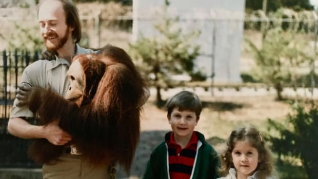 Zookeeper Dick Haskin poses for a photo with Chewy, a sumatran orangutan, and two young visitors at the Lincoln Children’s Zoo.