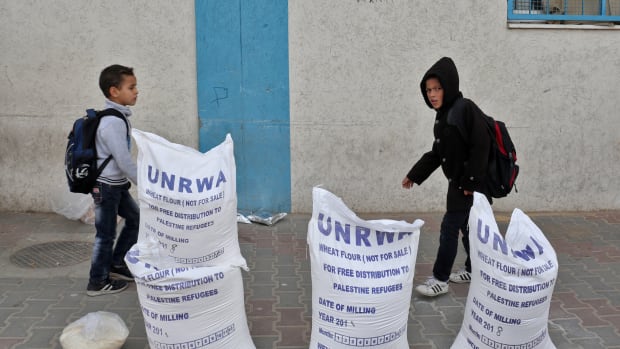 Palestinian schoolboys walk past sacks of flour outside an aid distribution center run by the United Nations Relief and Works Agency, in Rafah in the southern Gaza Strip, in December of 2018.