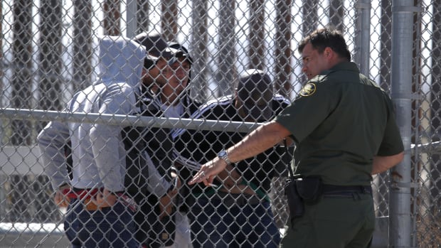 A U.S. Border Patrol agent talks with detained migrants at the border of the United States and Mexico on March 31st, 2019, in El Paso, Texas.