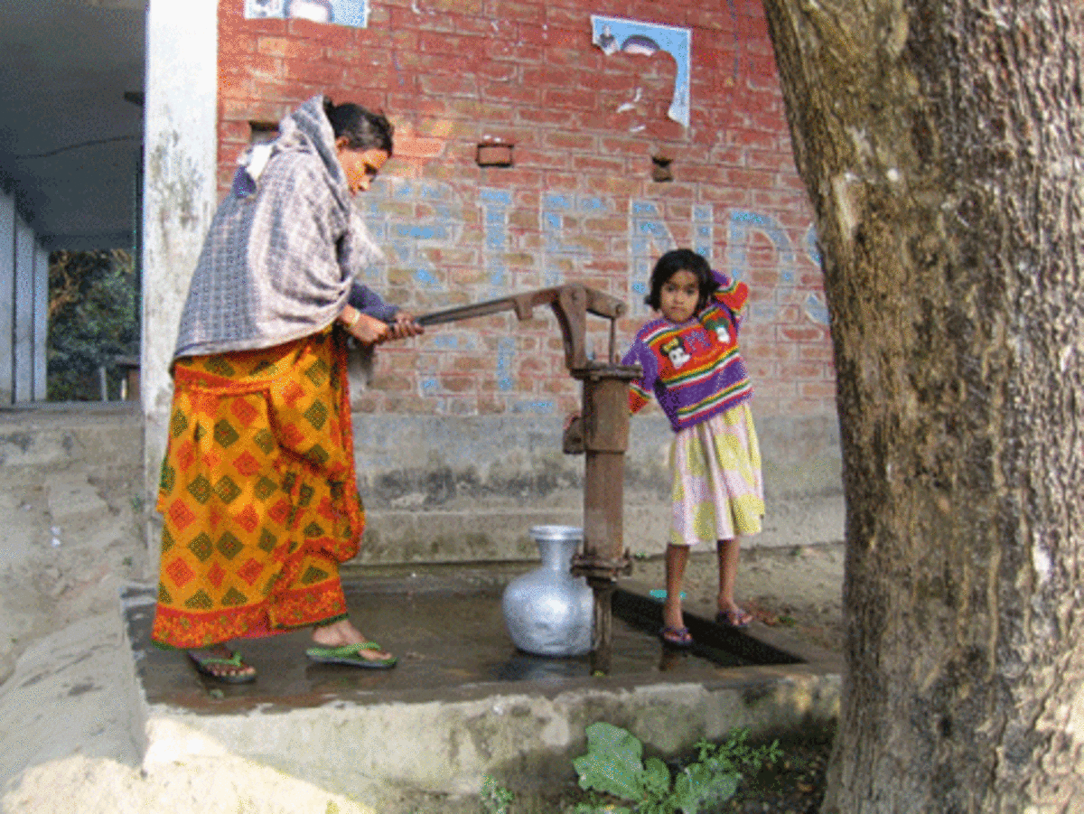 A woman pumps drinking water from a district well. (Courtesy of Charles Harvey)
