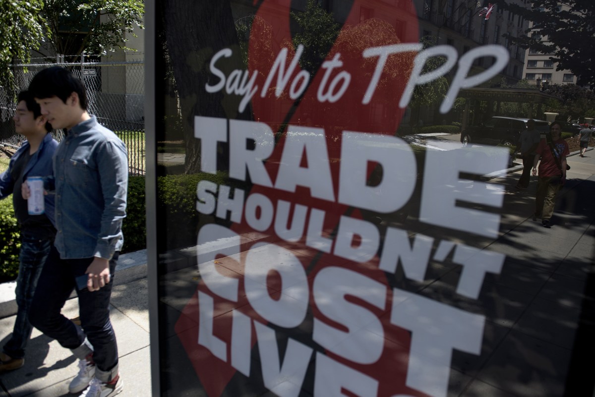 People pass an advertisement protesting the passage of the Trans-Pacific Partnership in Washington, D.C., on July 23, 2015. (Photo: Brendan Smialowski/AFP/Getty Images)