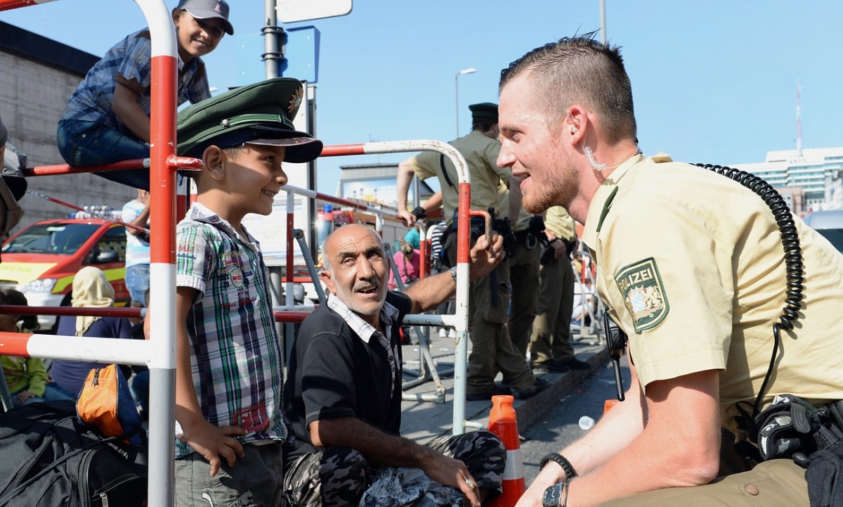 A German police officer talks to a young refugee as he waits for a bus outside the central railway station in Munich. (Photo: Christof Stache/AFP/Getty Images)