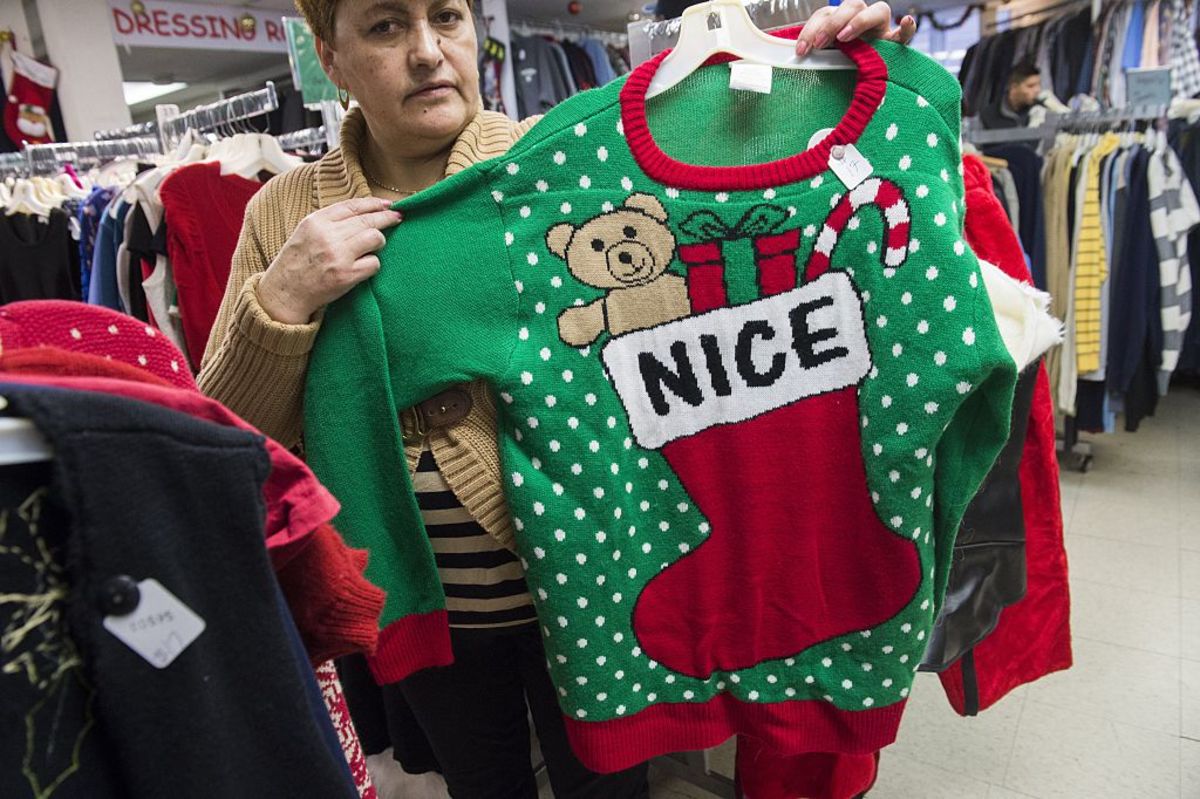 Irene Lopez, manager of Frugalista second hand store, shows off the  store's supply of ugly Christmas sweaters in Washington, D.C. (Photo: Saul Loeb/AFP/Getty Images)