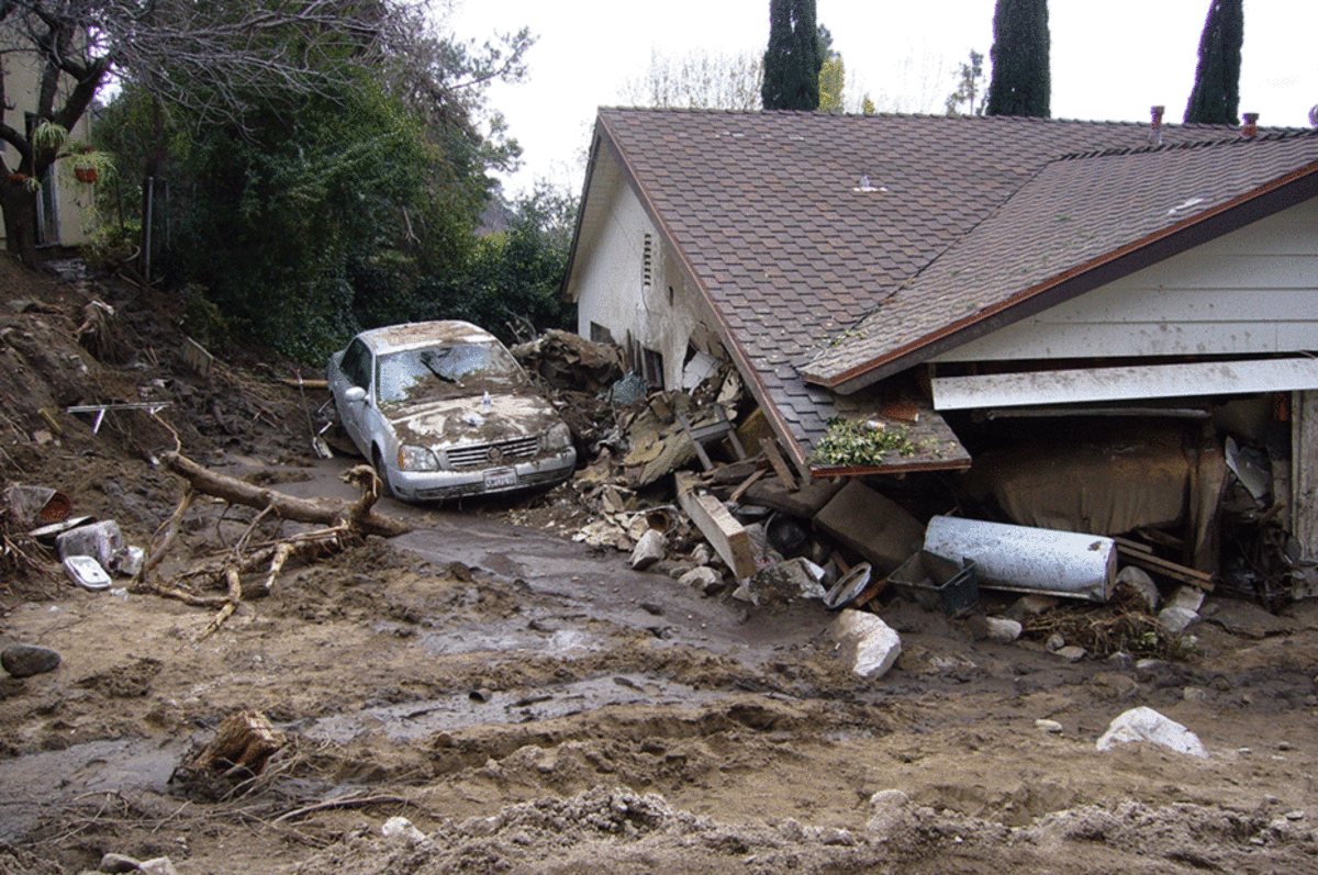 A house damaged by rainstorm-triggered  debris flows in Mullally Canyon, California, on February 6, 2010. The  drainage basin above this home was burned the previous summer by the  Station Fire, the largest fire in the history of Los Angeles County. (Photo: Susan Cannon/USGS)