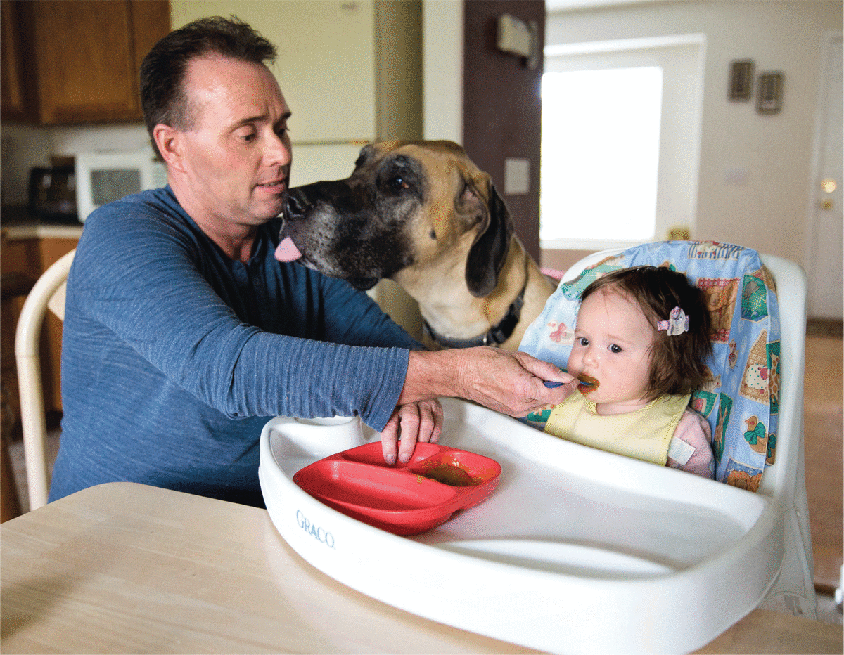 Ken Wehking, 46, spends time with Megan, his daughter by gestational carrier, and their 190-pound Great Dane, Dante. (Photo: Rebecca Stumpf)