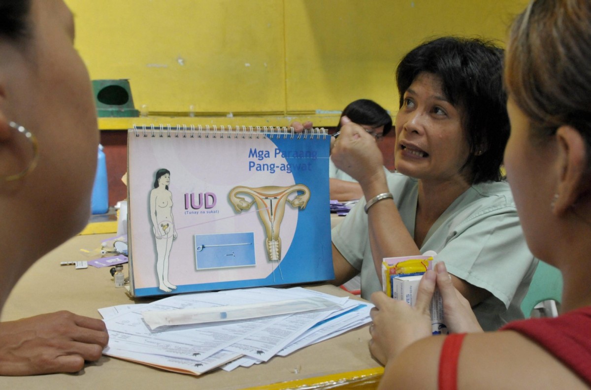A health worker teaches women how to use an intrauterine device during World Population Day in the Philippines.