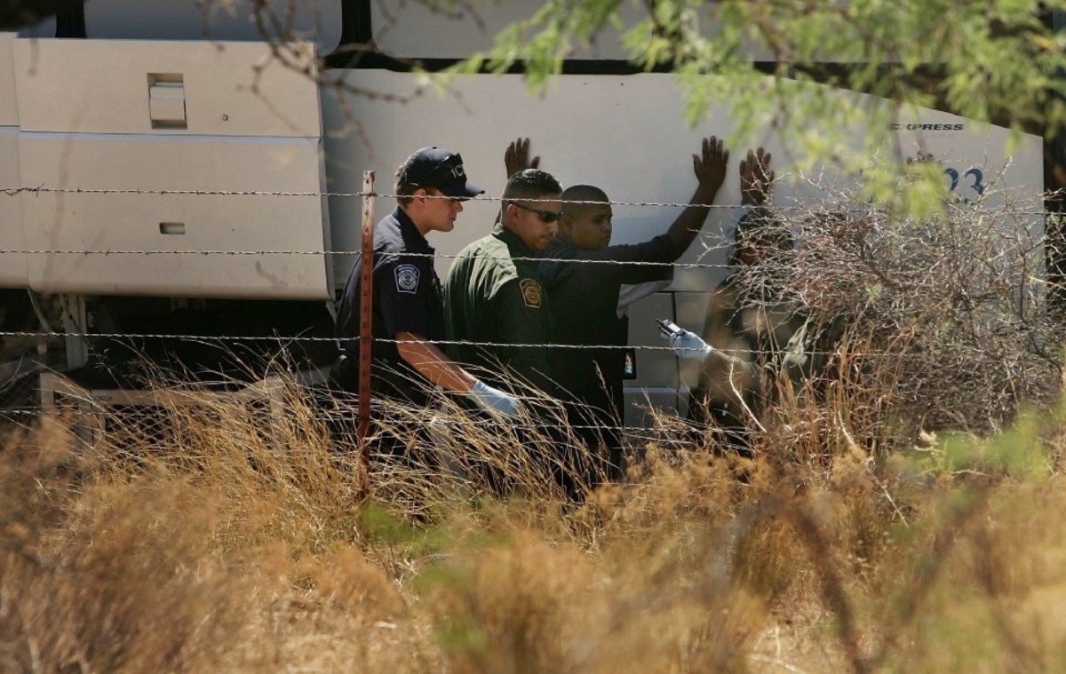 Immigration and Customs Enforcement (left) and Border Patrol agents detain a man at the Mexico border on June 16th, 2006.