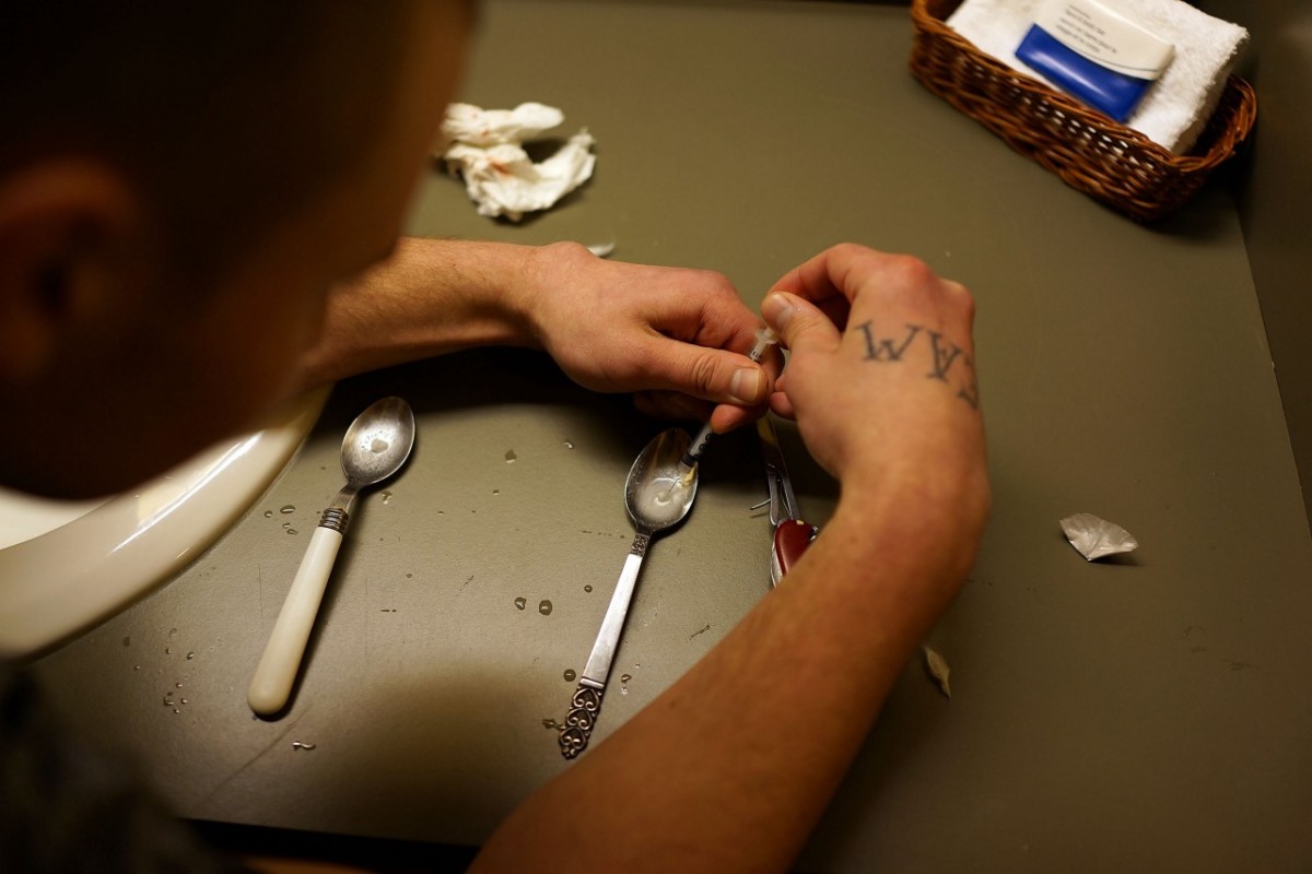 A heroin user prepares drugs to shoot intravenously.