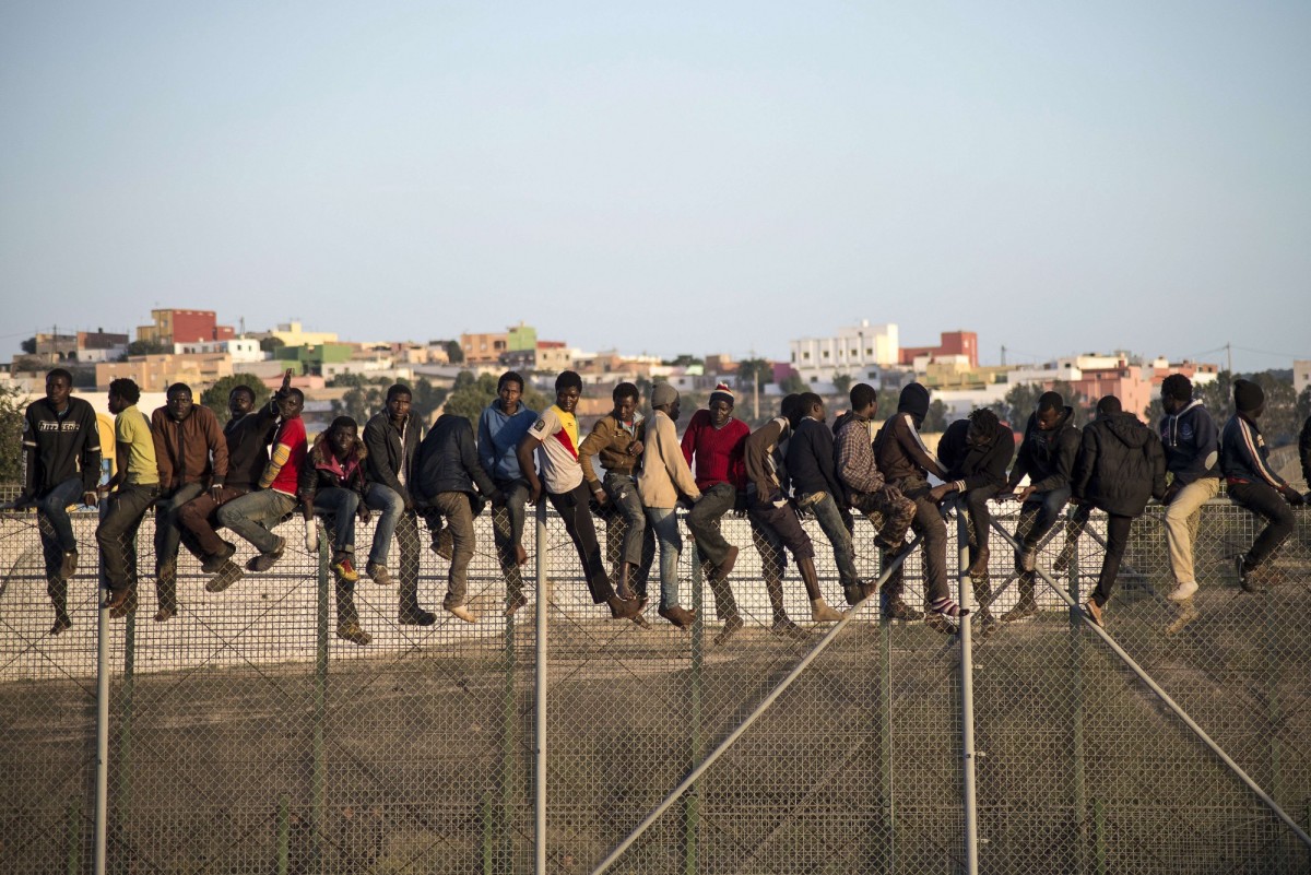 Would-be immigrants stand atop a boarder fence separating Morocco from the north African Spanish enclave of Melilla in 2014.