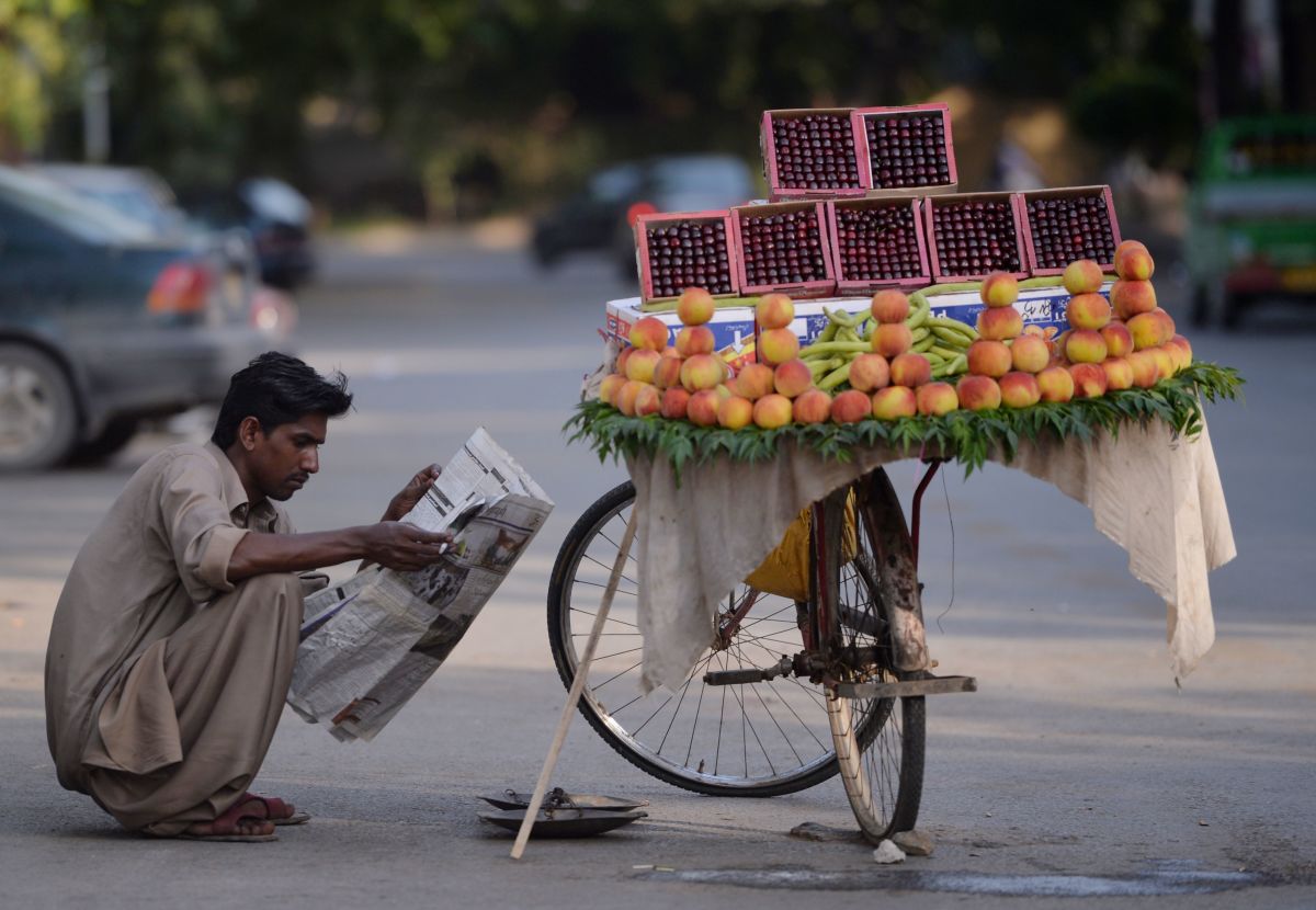 A fruit vendor reads a newspaper as he waits for customers on a street in Islamabad, Pakistan, on May 23rd, 2017.