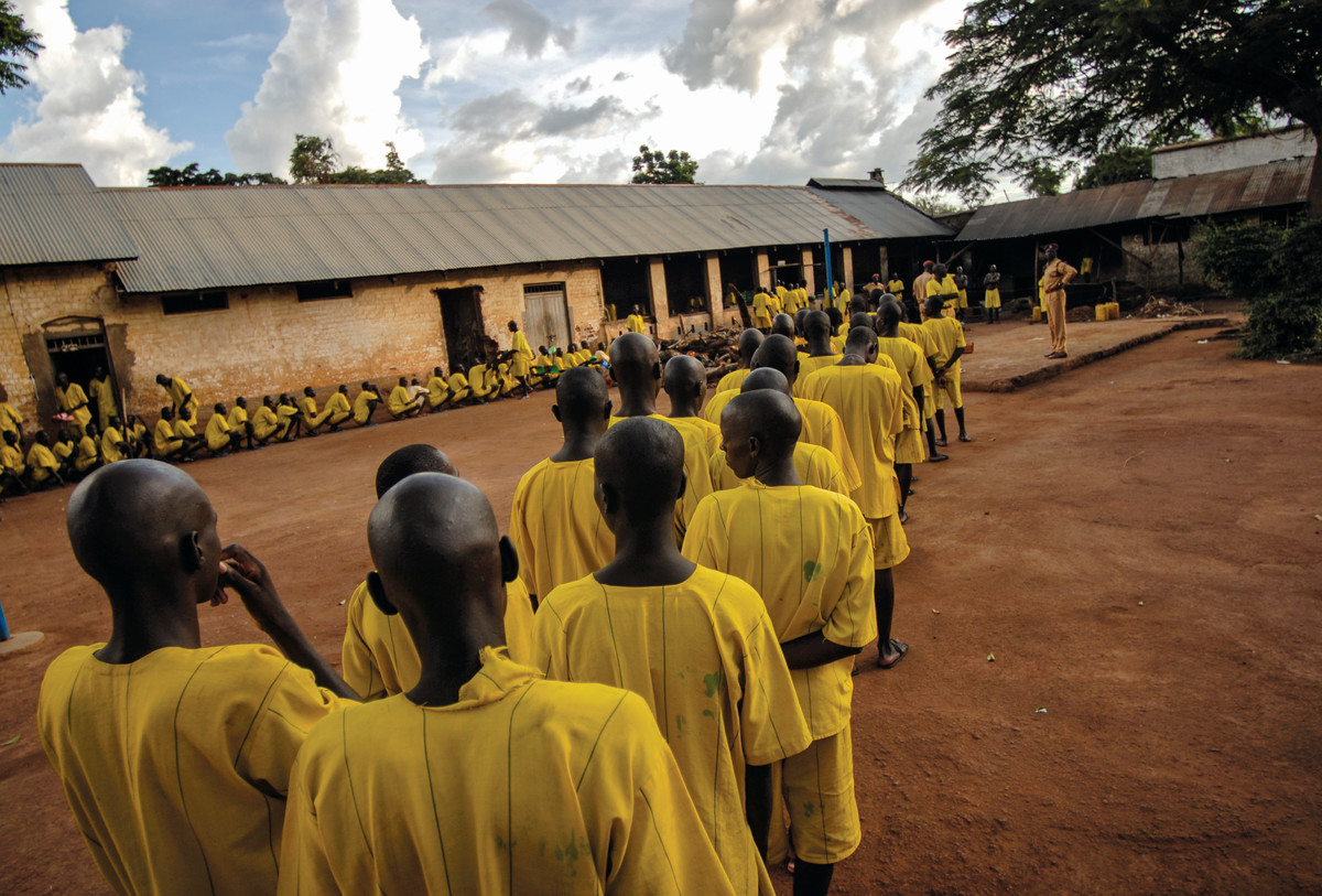 Prisoners, many of whom claim to be juveniles, line up for dinner at Lira Prison, Poor birth records make it difficult for Ugandan prison officials to remove younger prisoners from adult facilities.