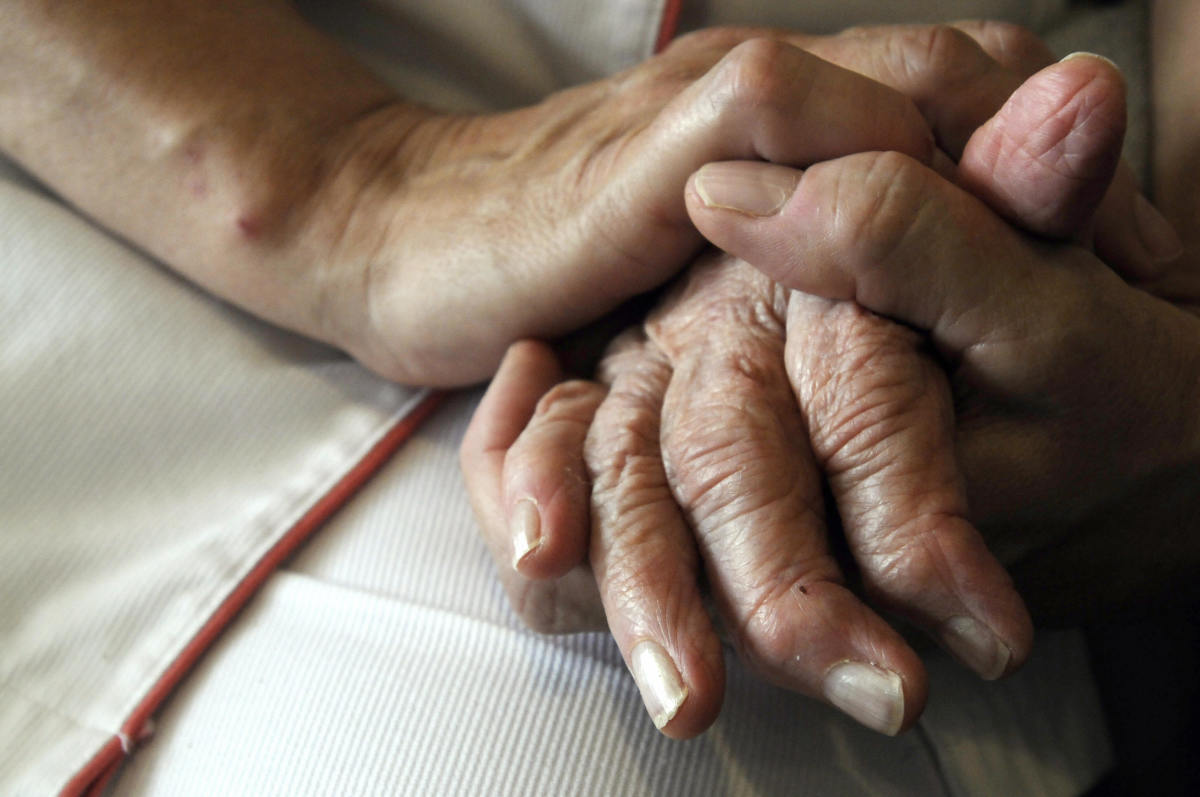 A nurse holds the hands of a person suffering from Alzheimer's disease.