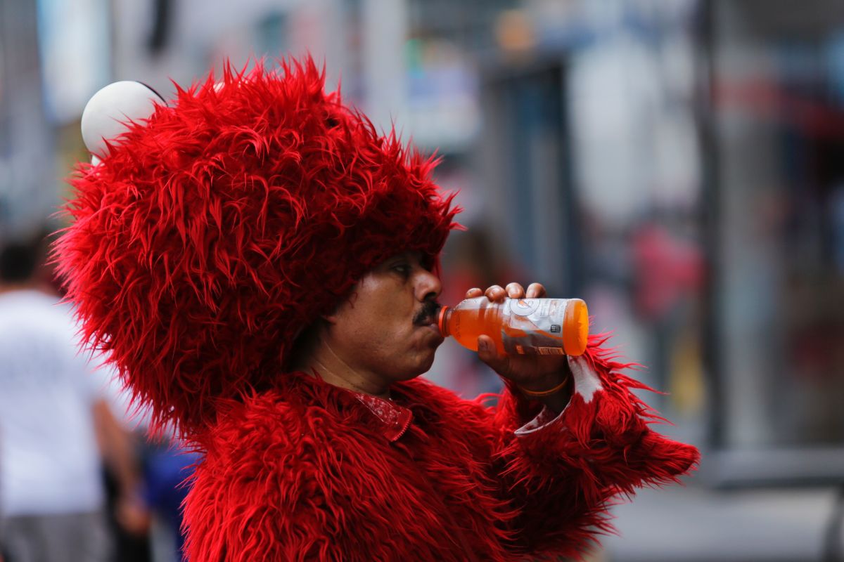 A man dressed as Elmo drinks to keep hydrated at Times Square during a sunny day as hot temperatures continue in New York on July 21st, 2017.