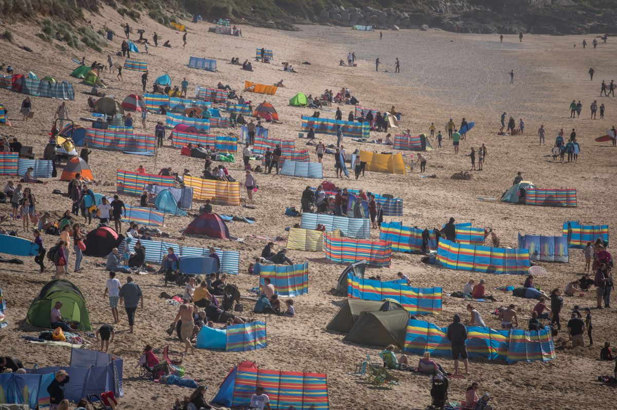 People gather on Fistral beach as surfers compete in a heat of the World Surf League Boardmasters Quicksilver Open at the annual Boardmasters festival on August 9th, 2017, in Cornwall, England. Since 1981, the Boardmasters surfing competition has been held in Newquay and is now part of a larger five-day surf, skate, and music festival. It attracts professional surfers from across the globe to compete on the Cornish beach that is seen by many as the birthplace of modern British surfing.