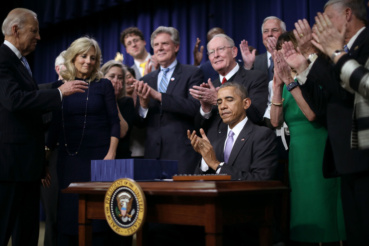 Surrounded by advocates and lawmakers, President Barack Obama applauds after signing the 21st Century Cures Act into law on December 13th, 2016, in Washington, D.C.