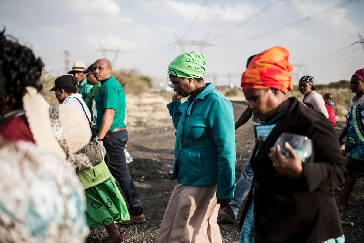 Widows of deceased striking miners who were killed during the Marikana massacre, walk from the memorial site, during the event's fifth anniversary in Marikana, on August 16, 2017. Thousands of South African miners sang remembrance songs on August 16, 2017, at the site of the 2012 Marikana massacre where police shot dead 34 strikers, as campaigners demanded prosecutions and compensation. The 34 miners were gunned down after police were deployed to break up a wildcat strike that had turned violent at the Lonmin-owned Marikana platinum mine, northwest of Johannesburg.
