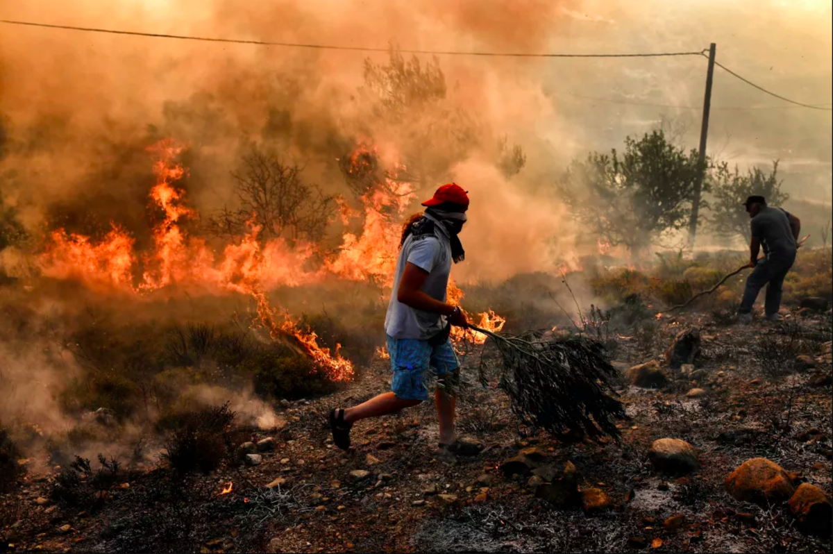 A man runs away from flames as fire burns the land, east of the Greek capital of Athens on August 15th, 2017. The army was called in to assist firefighters around Kalamos, 30 miles east of Athens, where a fire has been burning since August 13th. In all, 146 fires have broken out across Greece since then, according to authorities.