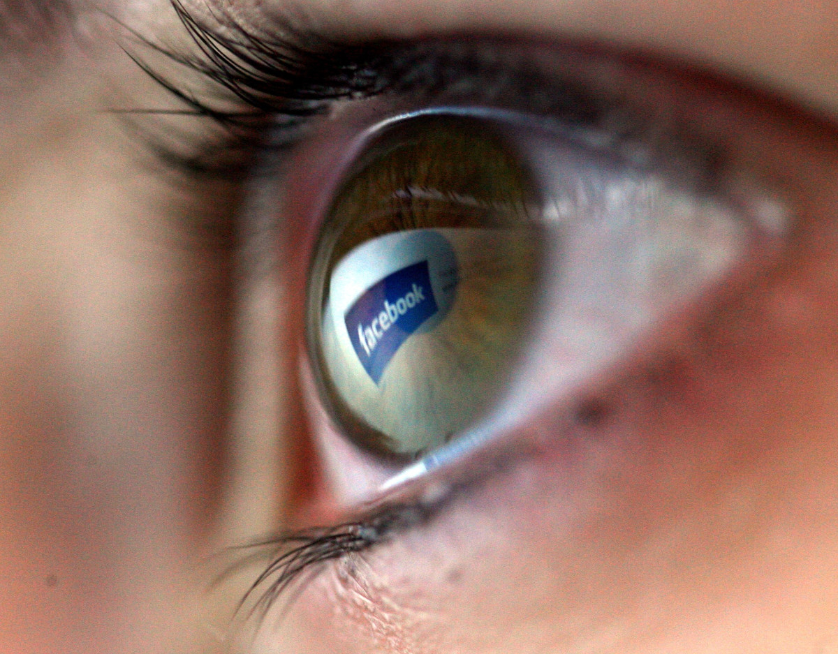 In this photo illustration the Facebook logo is reflected in the eye of a girl.