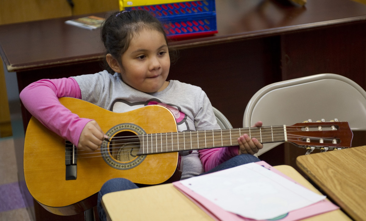 A young girl plays the guitar during guitar class at the Mariachi Academy in Harlem, New York.