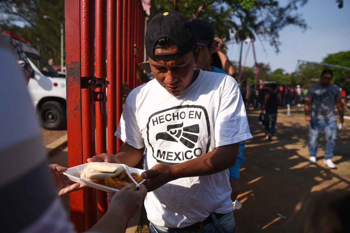 Central-American migrants taking part in the "Migrant Via Crucis" caravan toward the United States receive breakfast as they camp at a sport complex in Matias Romero, Oaxaca State, Mexico.