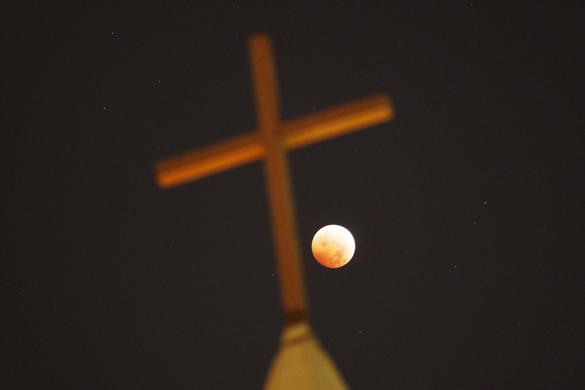 A religious cross is seen as the moon is illuminated by sunlight reflected off the Earth during a total lunar eclipse on October 8th, 2014, in Los Angeles, California.