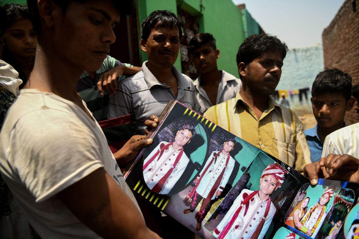 Neighbors look through the wedding pictures of 24-year-old Sunil Kumar, who died after getting crushed under the debris of a ceiling that fell in heavy storm winds in Kheragarh on the outskirts of Agra on May 4th, 2018.