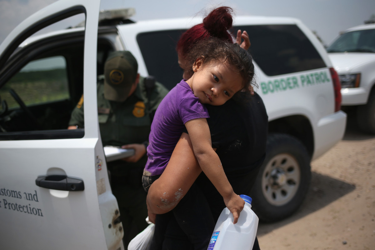 A mother and child await transport to a processing center for undocumented immigrants on July 24th, 2014, in Mission, Texas.
