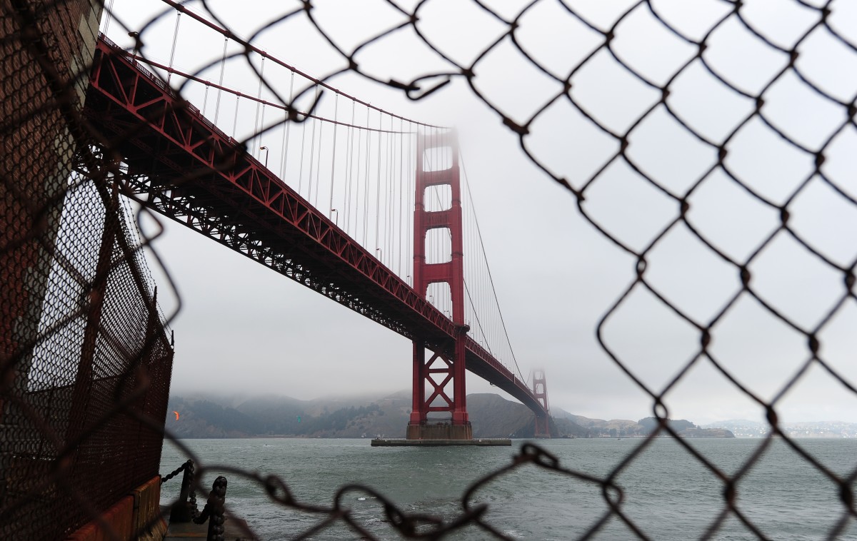A view of the Golden Gate Bridge is seen through a hole in a fence closing off a part of Fort Point in San Francisco.
