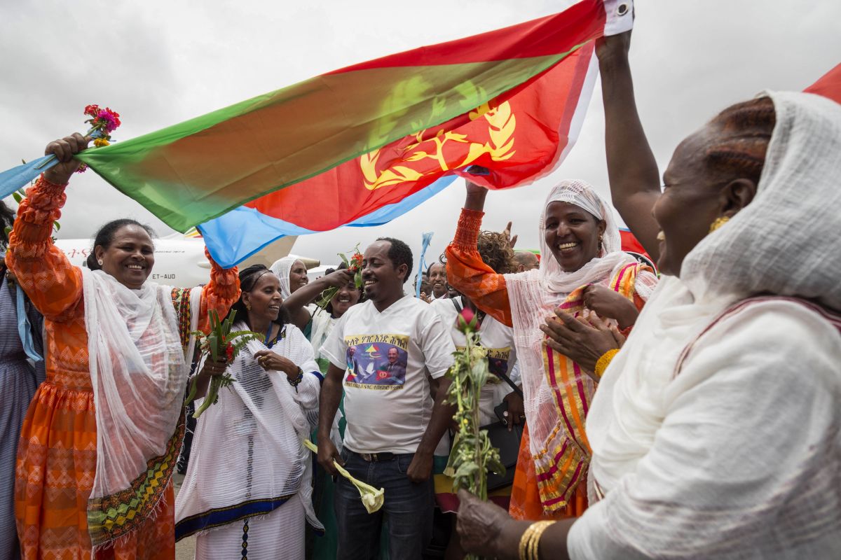 Eritrean women hold up their nation's flag on July 18th, 2018, to welcome passengers on the flight from Ethiopian capital Addis Ababa at Asmara International Airport.