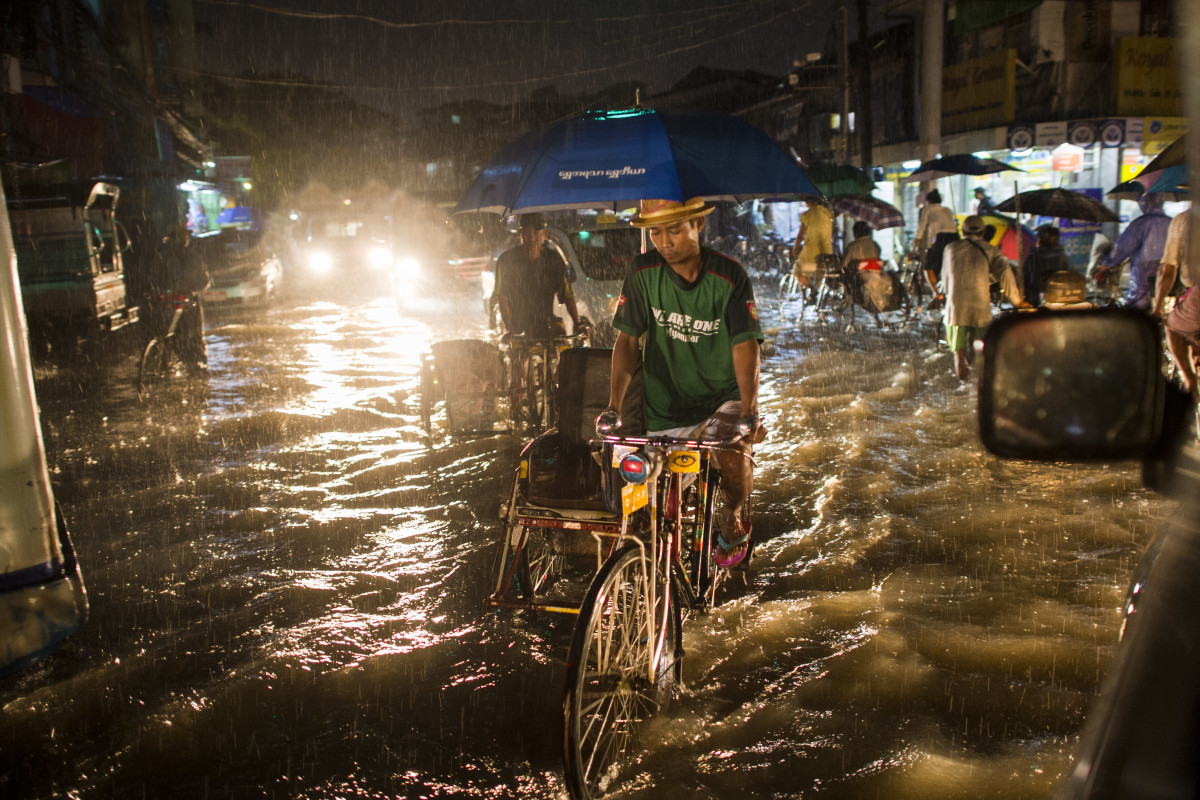A man rides a tri-shaw along a flooded road in Yangon on August 2nd, 2018.