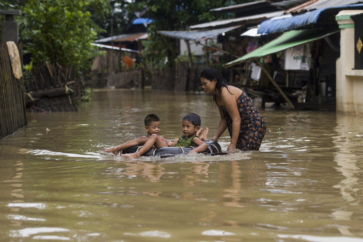 A woman pushes children on an inner-tube through a flooded street in Shwegyin, Bago region, on August 2nd, 2018.