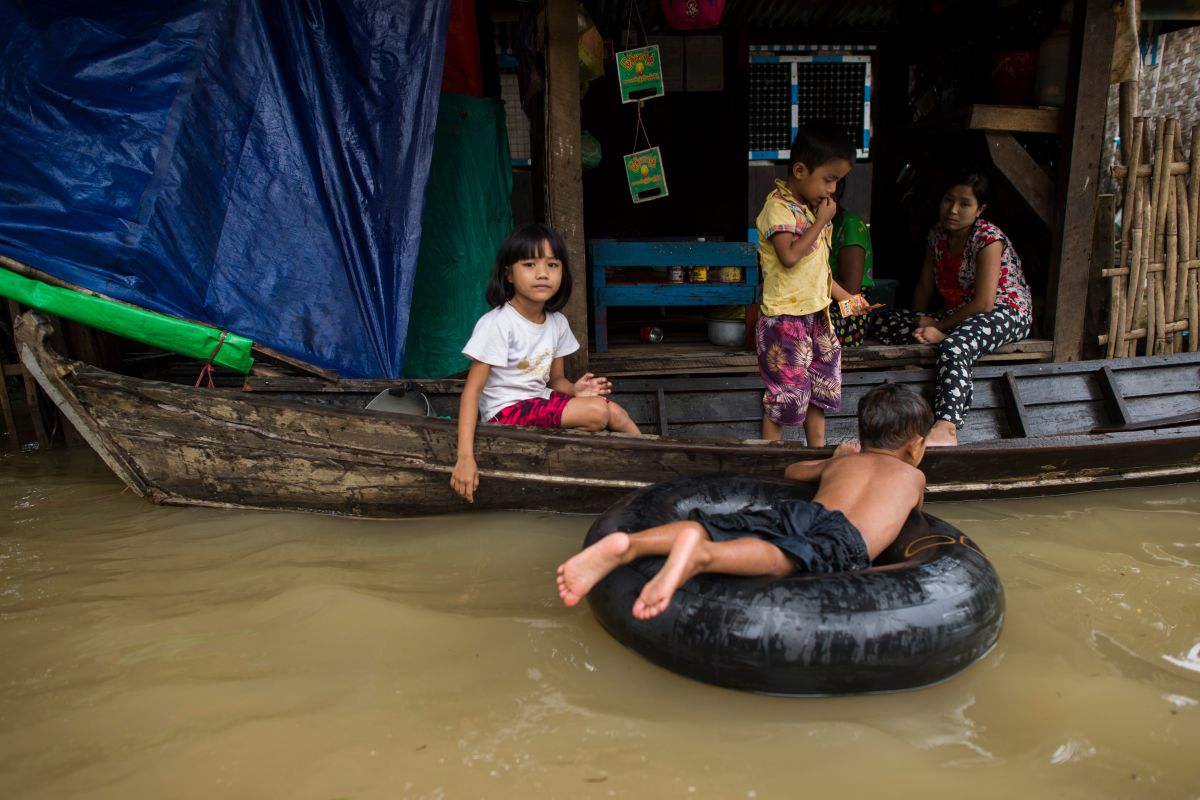 Young people sit in a boat outside a home surrounded by floodwaters in Shwegyin, Bago region, on August 2nd, 2018.
