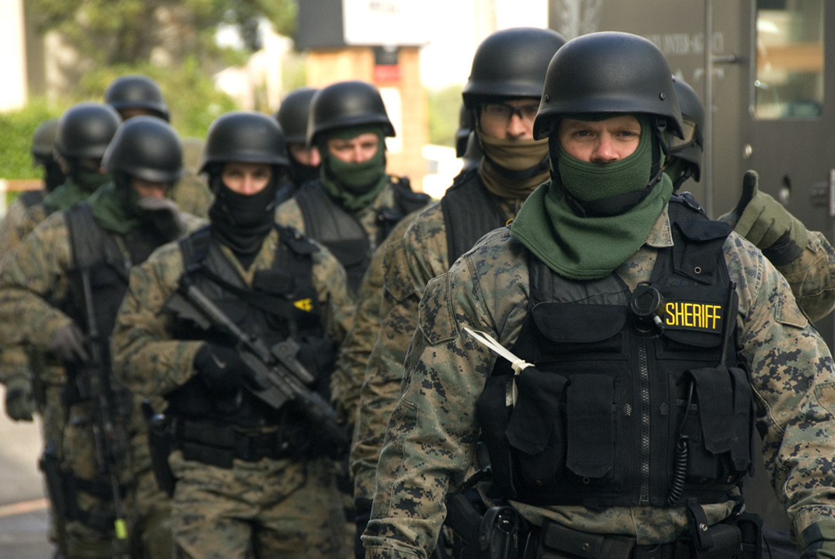 SWAT team members, some armed with assault rifles, prepare for an exercise.