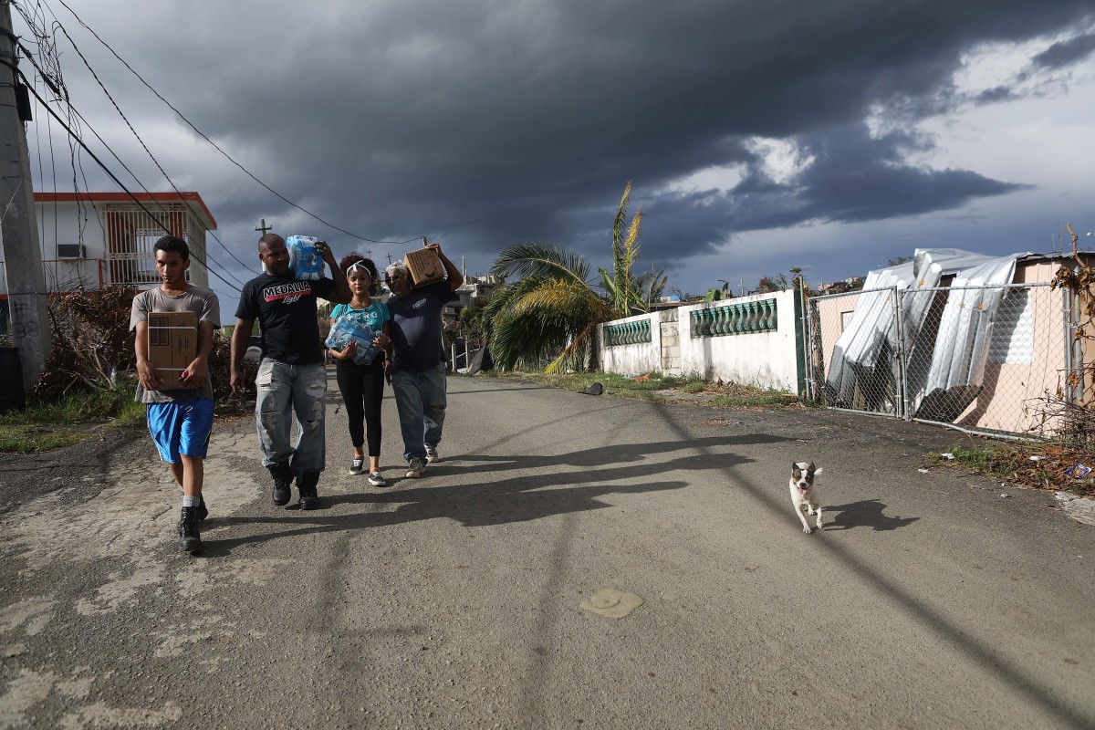 Puerto Rican residents carry water and Meals-Ready-to-Eat received from FEMA about two weeks after Hurricane Maria swept through the island, on October 5th, 2017, in San Isidro, Puerto Rico.
