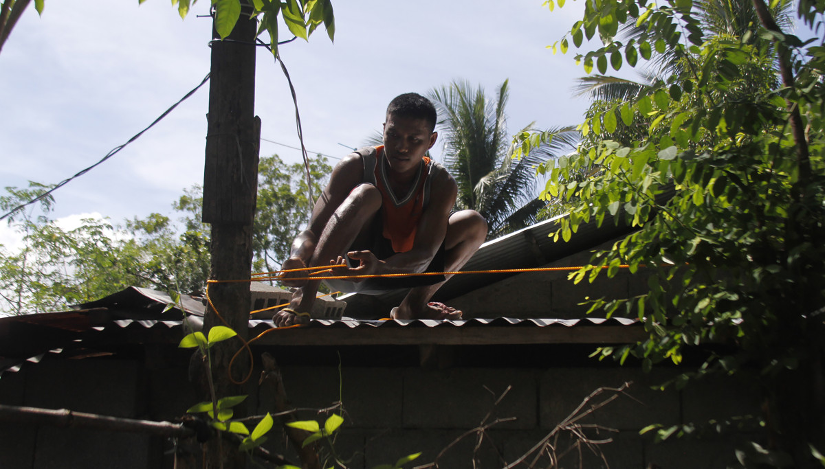 A resident secures the roof of his house to a tree in preparation for Super Typhoon Mangkhut in Candon City, Ilocos Sur province, north of Manila, on September 13th, 2018. The super typhoon, a Category 4 storm, roared toward the Philippines on September 13th, packing fierce winds and heavy rains that are expected to strike the disaster-prone nation during the weekend before moving on to China.