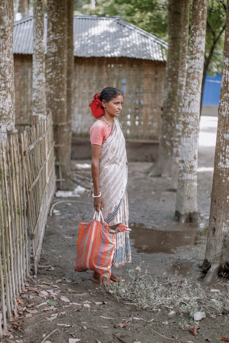 Laxmi Rani and her Hindu family chose not to resettle in India. She lives in a former chhitmahal with about 10 other Hindu families and is pictured here heading out to sell ducks. Since becoming part of Bangladesh, their area has seen the development of roads, electricity, a temple, a mosque, a clinic, and a school. Prior to then, no government officials had entered the area. Many, but not all, of the people in her community now have voter ID cards.