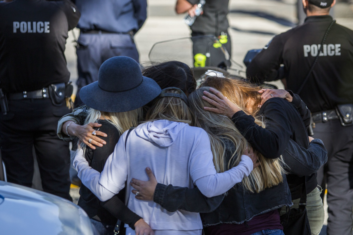 Friends hug outside the Los Robles Medical Center in Thousands Oaks, California, on November 8th, 2018, as they pay tribute to Ventura Country Sheriff's Sergeant Ron Helus, who was killed in a shooting at Borderline Bar & Grill the night before.