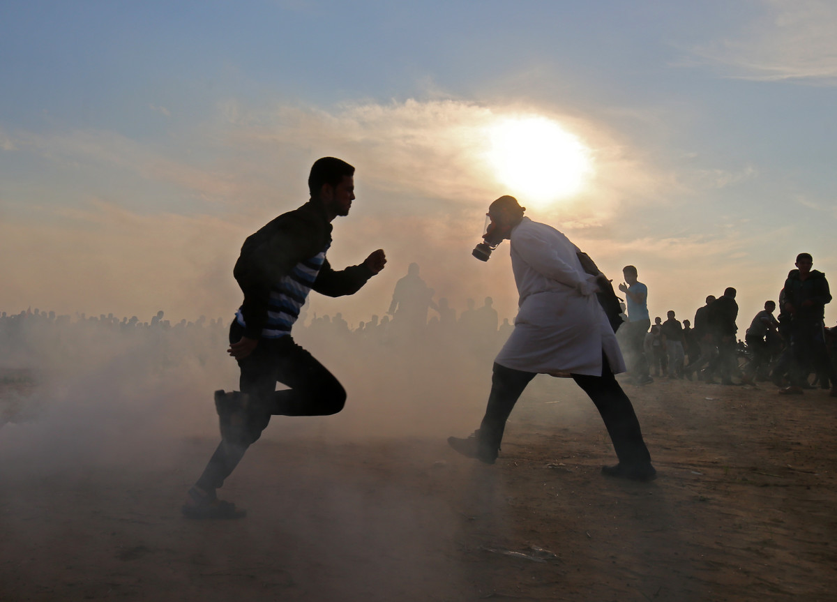 Palestinians run for cover from tear gas during clashes near the border between Israel and Khan Yunis in the southern Gaza Strip on November 9th, 2018.