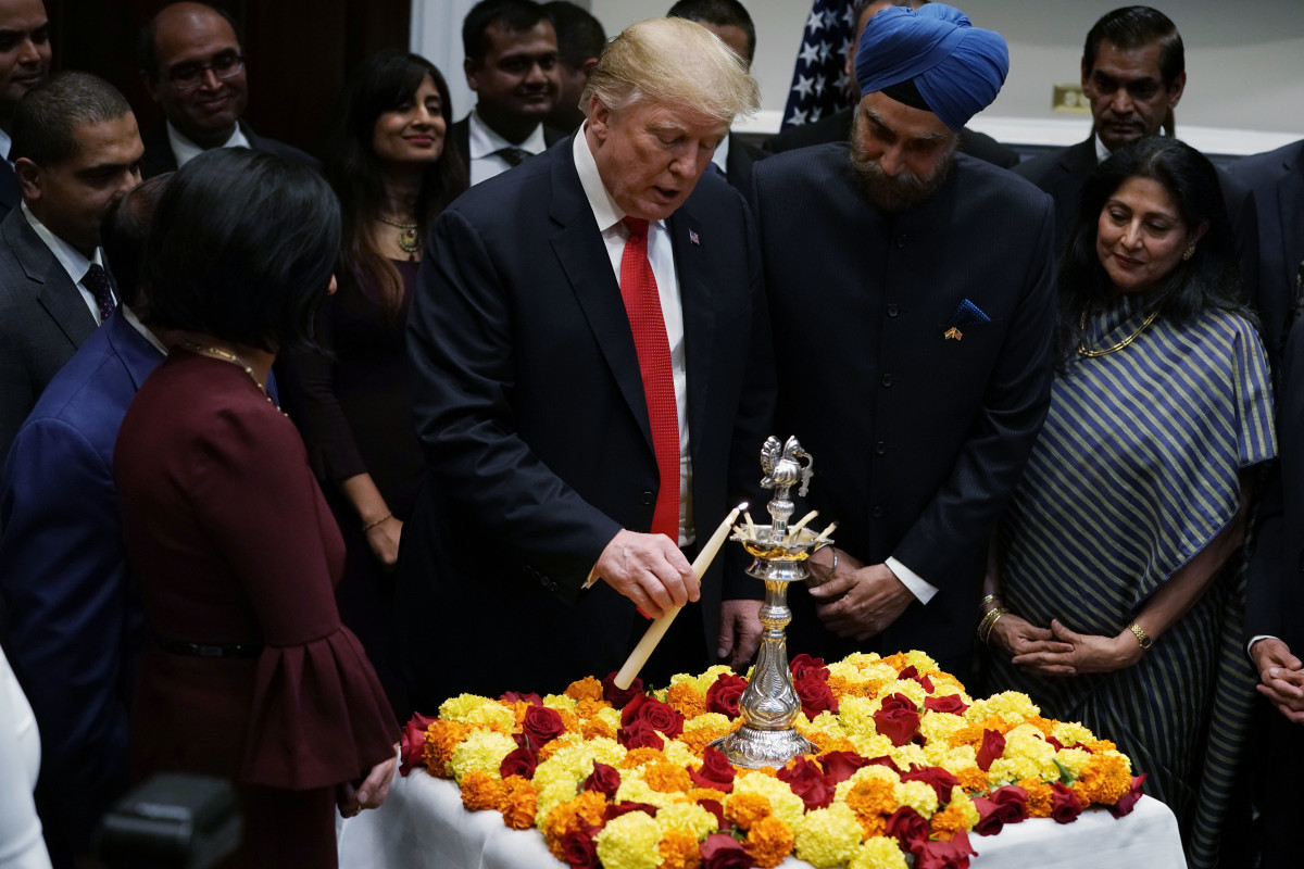 President Donald Trump lights a "diya," or oil lamp, as Indian Ambassador to the United States Navtej Singh Sarna looks on during a Diwali ceremony in the Roosevelt Room of the White House on November 13th, 2018, in Washington, D.C. Trump was criticized online for tweets about the ceremony that mentioned Sikhs, Jains, and Buddhists but omitted Hindus, the primary celebrants of the holiday.