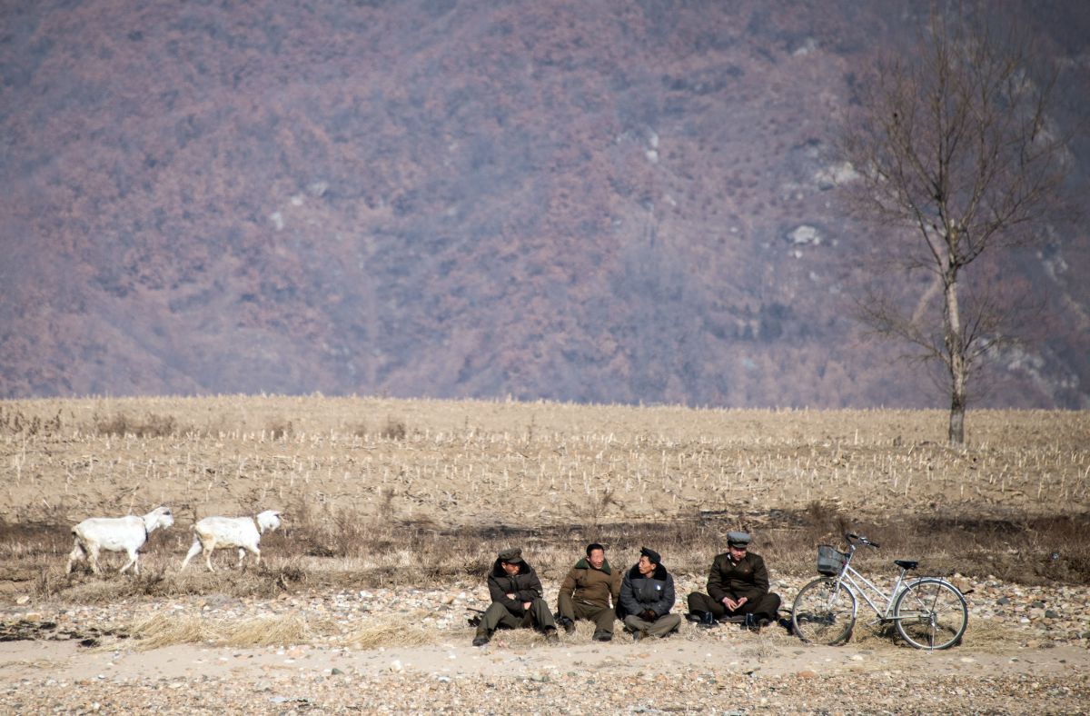 North Korean shepherds sit by the Yalu River banks near the town of Sinuiju across from the Chinese border town of Dandong.